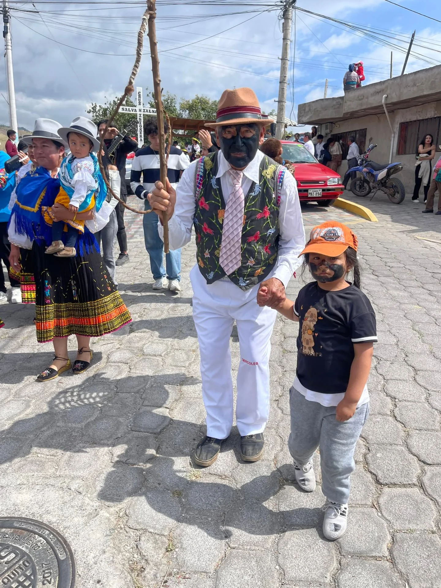 El Negro con sombrero, chaleco bordado y bastón, acompañado por un niño en el desfile de San Pedro.