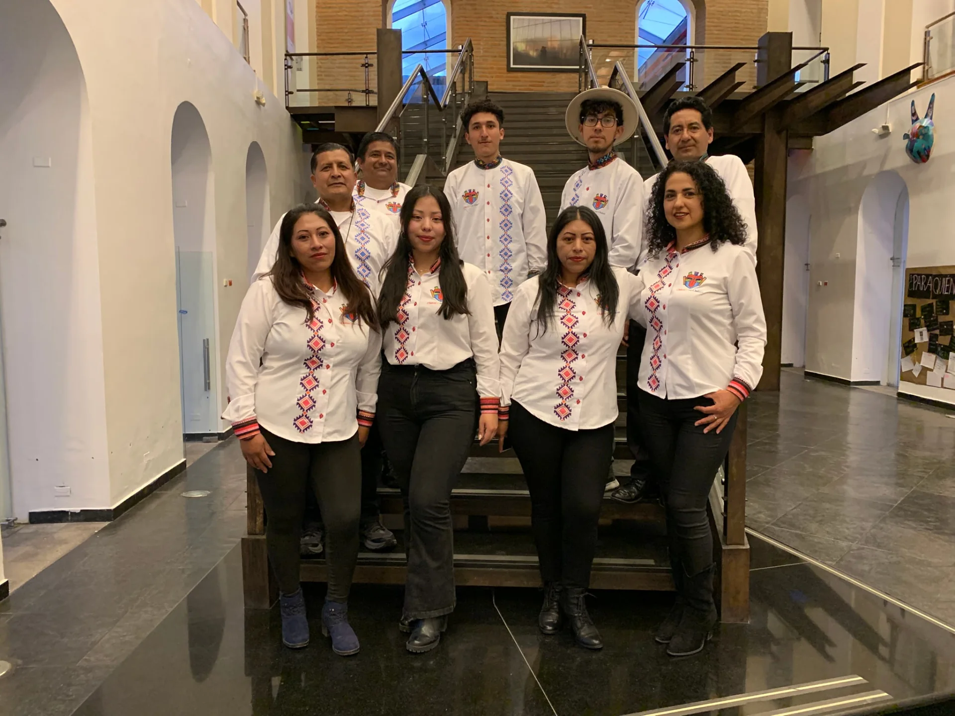 Integrantes de Chávez o no Chávez con camisas bordadas, reunidos frente a una escalera.